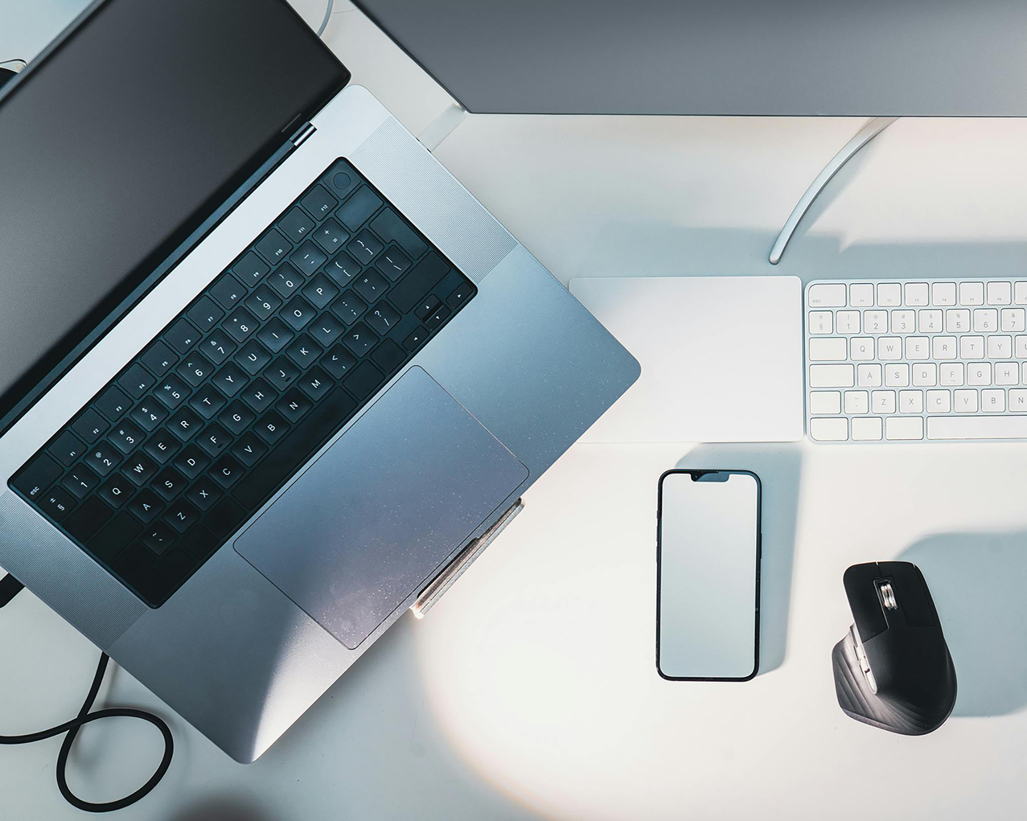 A laptop, telephone, and mouse on a white table. 