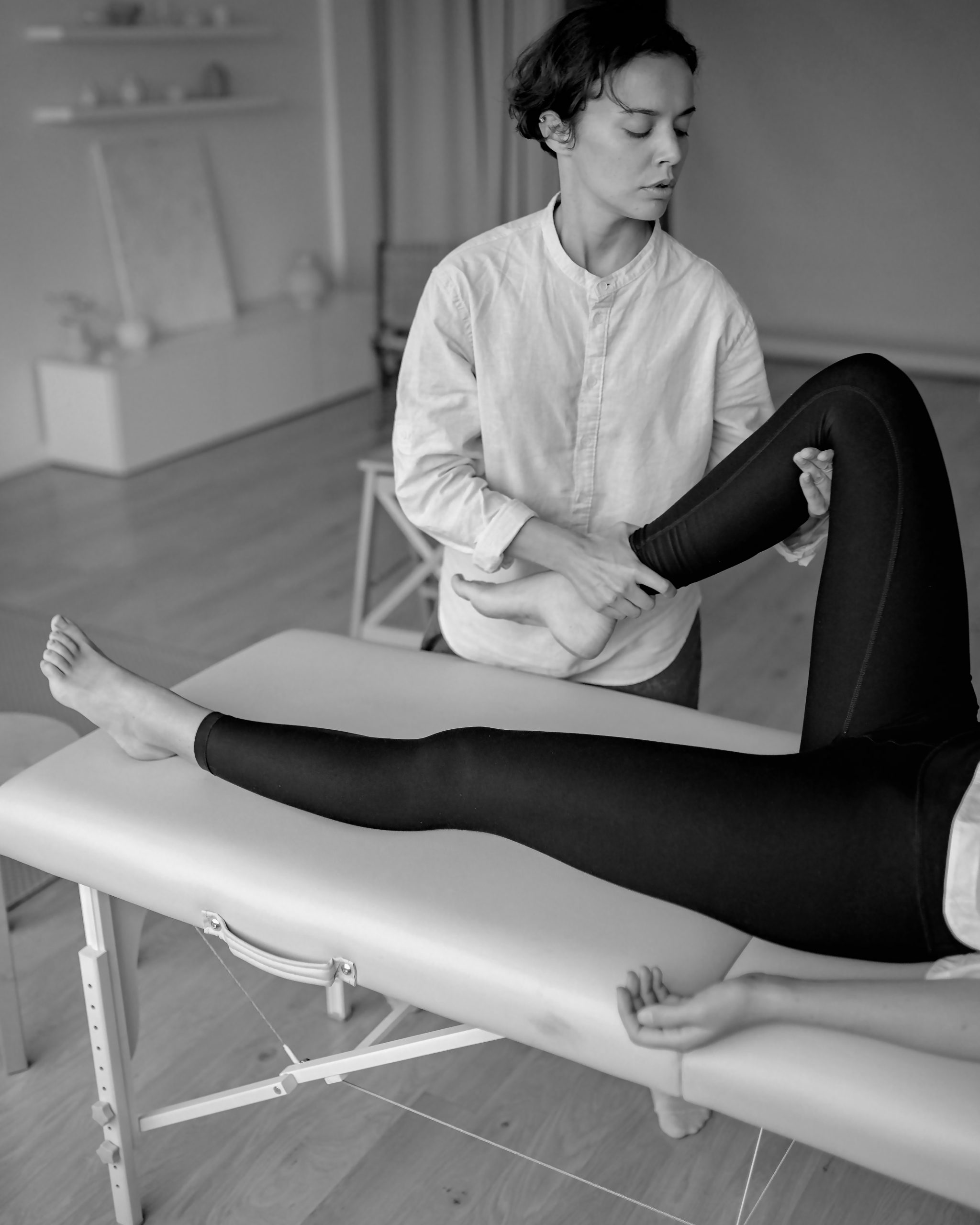 A physical therapist bending a patients leg at the knee. 