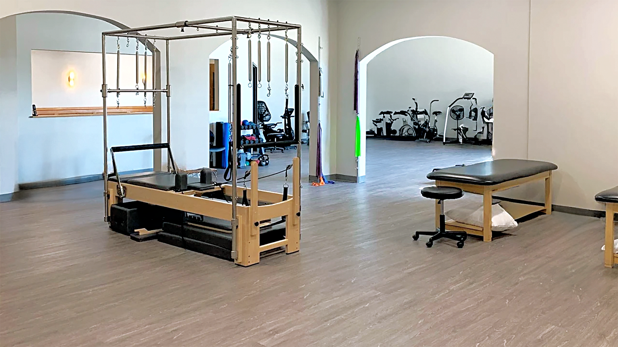 A large room with wooden floors, physical therapy tables, and equipment.