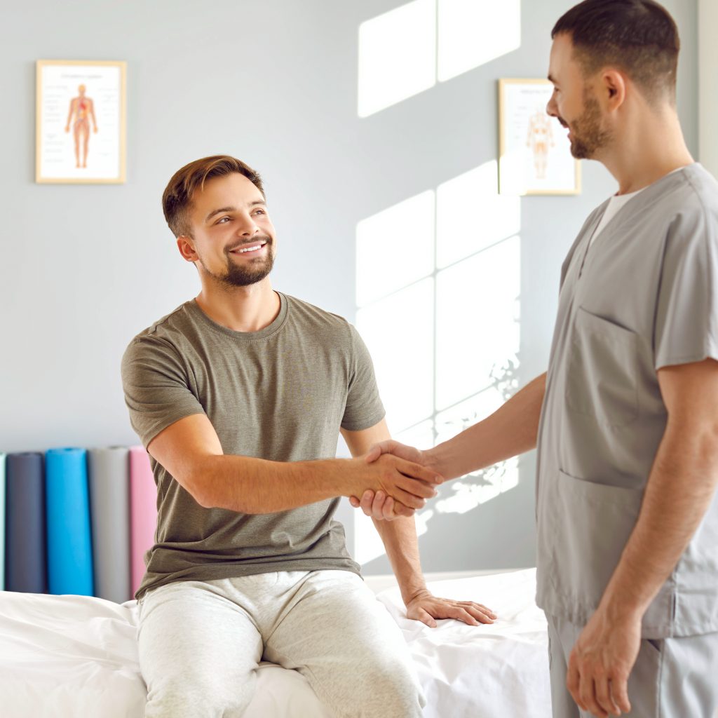 A patient shaking a pyshical therapists hand and smiling. 