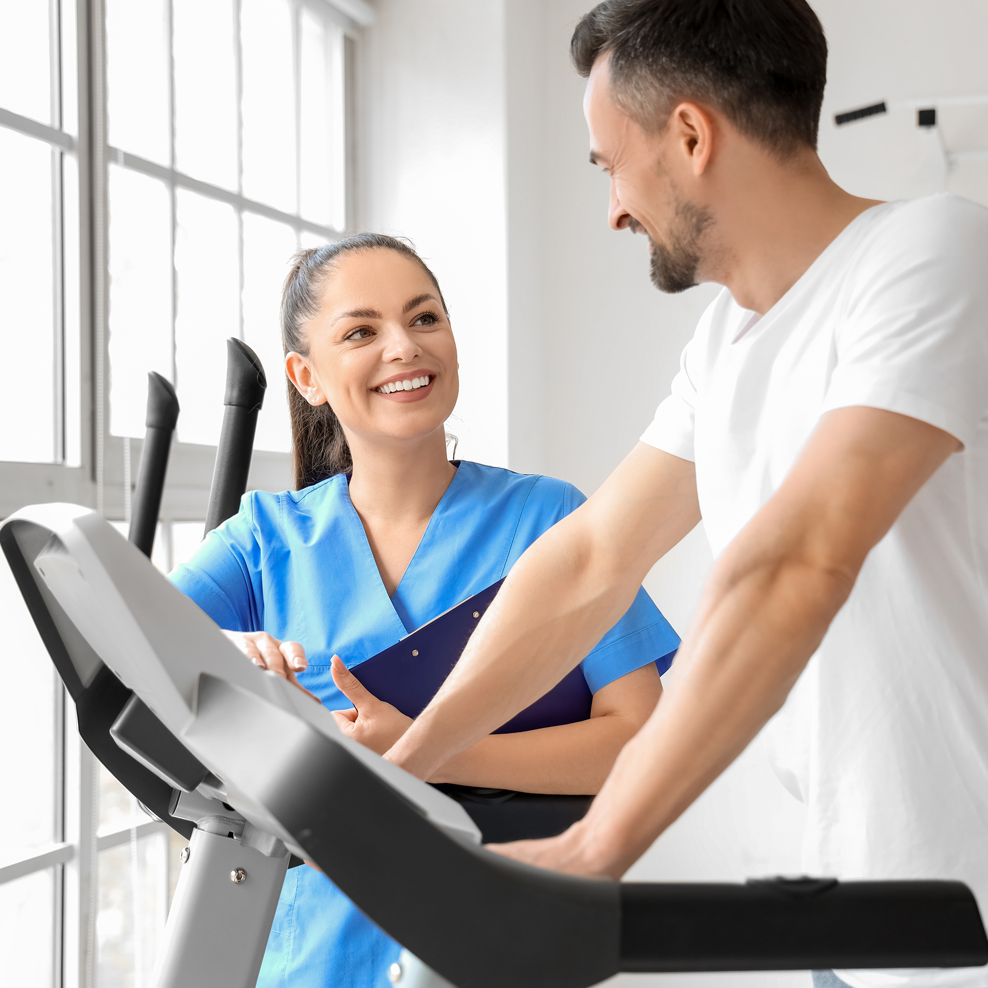 A physical therapist coaching a patient who is walking on the treadmill.